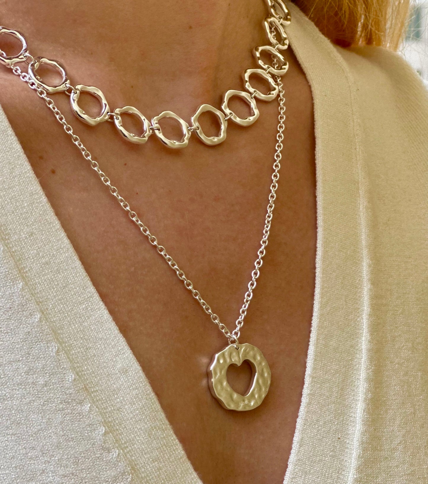 Amor necklace. Chain with heart pendant. Irregular circle pendant with a heart inside. 925 sterling silver alterego chunky jewelry. Next to the irregular circles silver necklace in model