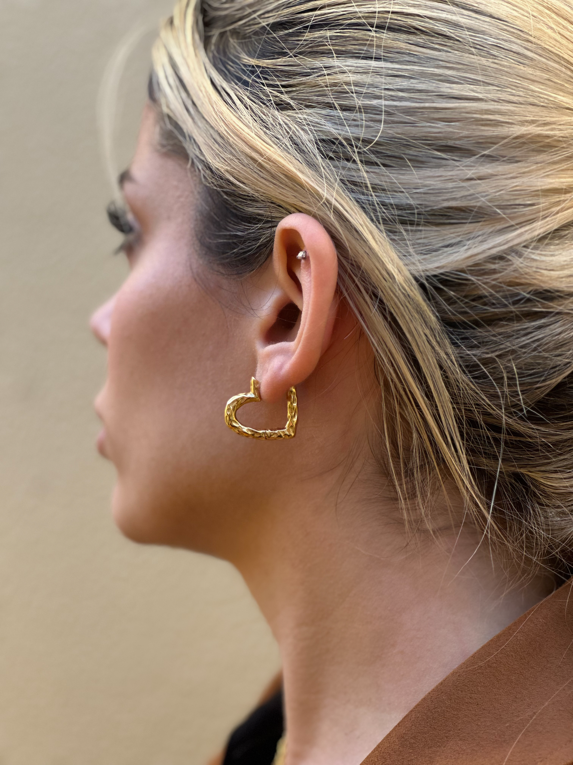 Hearts 18k gold irregular hoops earrings in model earlobe